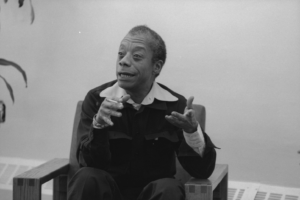 James Baldwin at the African Center, sitting in chair